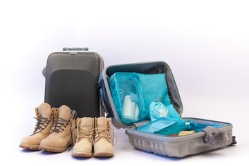 Travel concept with luggage. prepare accessories and travel items isolated on white background. Travel plan, trip vacation, tourism, Open traveler's bag with clothing. Open gray suitcase on the floor.