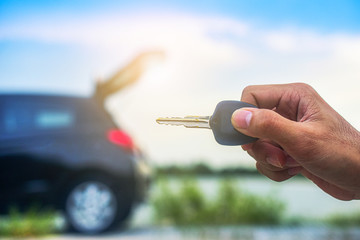 Hand holding Key and Car parked on road background