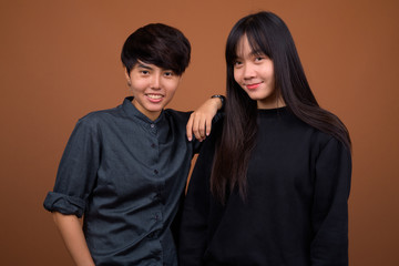 Young Asian lesbian couple together and in love against brown ba