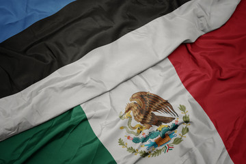 Naklejka premium waving colorful flag of mexico and national flag of estonia. macro