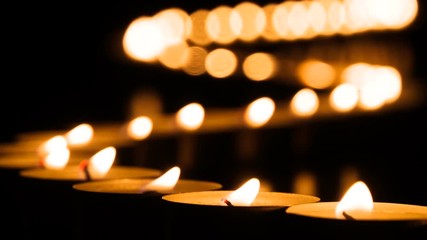 Ornate Line of Burning Candles. Winding line of burning candles stretching into the distance on a black background. The movement of air is waving lights
