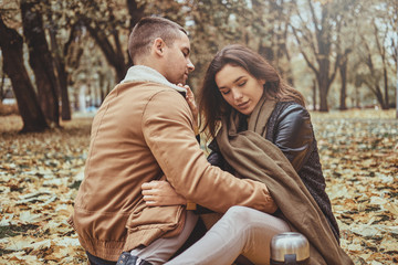 Beautiful couple has a date at autumn park full of yellow maple leaves.