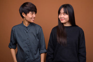 Young Asian lesbian couple together and in love against brown ba