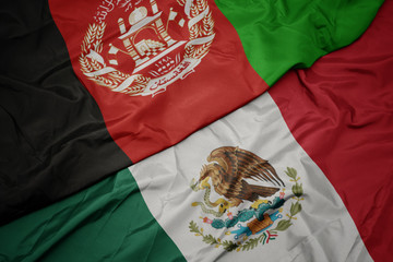 Naklejka premium waving colorful flag of mexico and national flag of afghanistan. macro