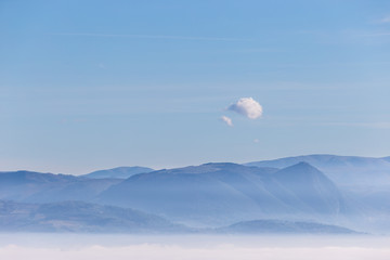 Fog filling a valley in Umbria (Italy), with mountains and hills beneath a blue sky with an...