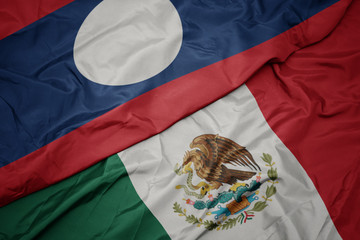Naklejka premium waving colorful flag of mexico and national flag of laos. macro