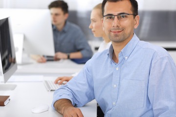 Fototapeta na wymiar Business people working together in modern office. Focus at happy smiling adult businessman or entrepreneur using pc computer. Teamwork and partnership concept. Casual dress style