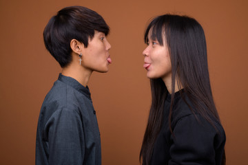 Young Asian lesbian couple together and in love against brown ba