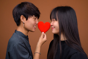 Young Asian lesbian couple together and in love against brown ba