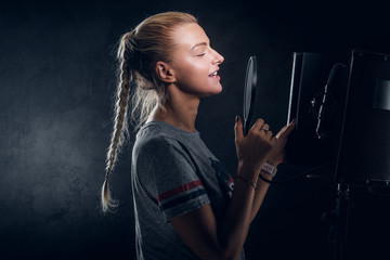 Charming cool student is singing her new song at recording studio.