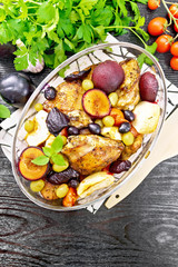 Chicken with fruits and tomatoes in glass pan on dark board top