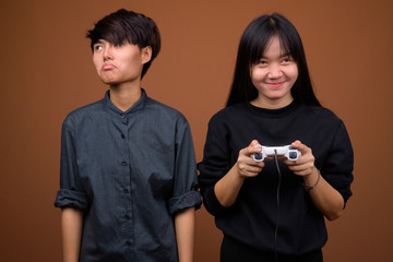 Young Asian lesbian couple together and in love against brown ba