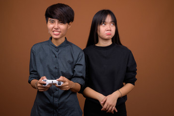 Young Asian lesbian couple together and in love against brown ba