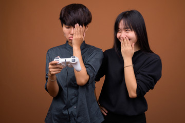 Young Asian lesbian couple together and in love against brown ba