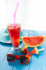 Watermelon and black glasses in the blue table on blurred blue hat background,