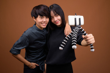 Young Asian lesbian couple together and in love against brown ba