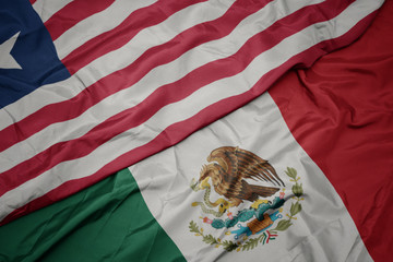 waving colorful flag of mexico and national flag of liberia. macro