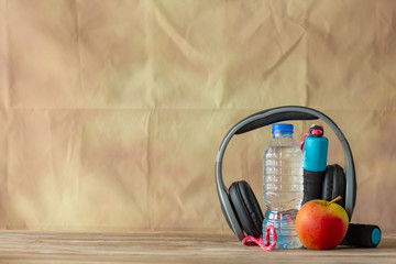 Earphone red apple and bottle water with jump robe on wooden colour background,