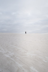 Fototapeta na wymiar Lone person on a gloomy winters day, walking through Lancelin Sand Dunes at sunrise before the crowds arrive.