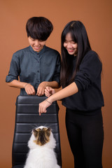 Young Asian lesbian couple together and in love against brown ba