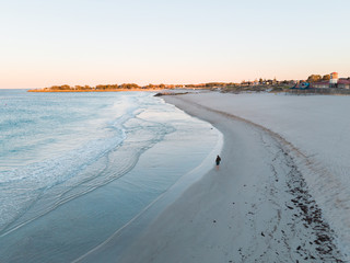 Beautiful drone photography of a man walking on Sorrento beach and ocean at sunrise, Perth Western...