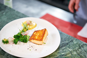 the finished dish in a restaurant kitchen . Salmon steak fillet and garnished with young broccoli. Restaurant menu, a series of photos of different dishes
