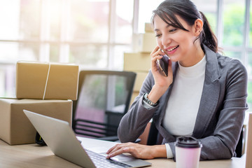 Happy young Asian woman answer phone from customer with her business online shopping at office.