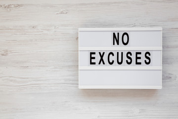 'No excuses' words on a modern board on a white wooden background, top view. Overhead, from above, flat lay. Copy space.