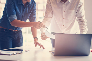 Obraz premium Two male architects in office discussing about construction project. Close up of engineer working with blueprints and laptop notebook.