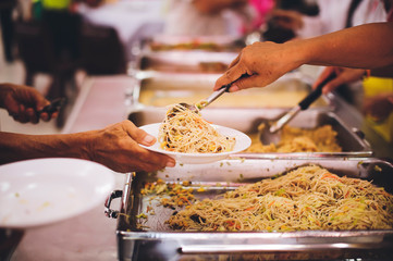 Volunteers are donating free charity food to homeless beggars: the concept of food needs in society.