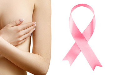 Young woman covers her breast near big pink ribbon.