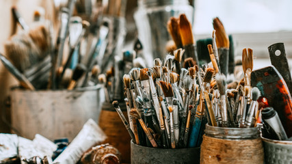Table with brushes and tools in an art workshop. Background. - obrazy, fototapety, plakaty