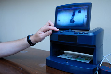 Man’s hand touching switch button on the receiver of the money detector