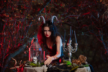 Beautiful witch with horns on her head is being prepared to make the witchcraft over the forest...