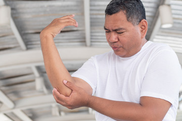 old senior man suffering from elbow joint pain or injury