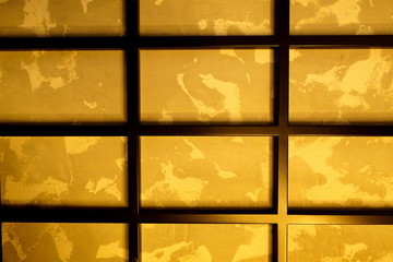 rectangular black metal grill on the wall, with a golden background.