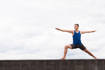 Fototapeta na wymiar young man in warrior asana doing yoga outdoor