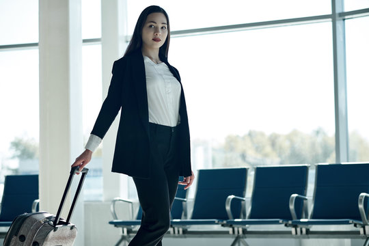 Young asian business woman in airport with trolley bag, waiting for departure