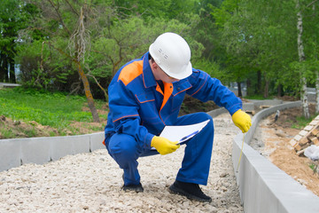 the builder checks the progress of laying curbstones, rubble mounds and keeps records
