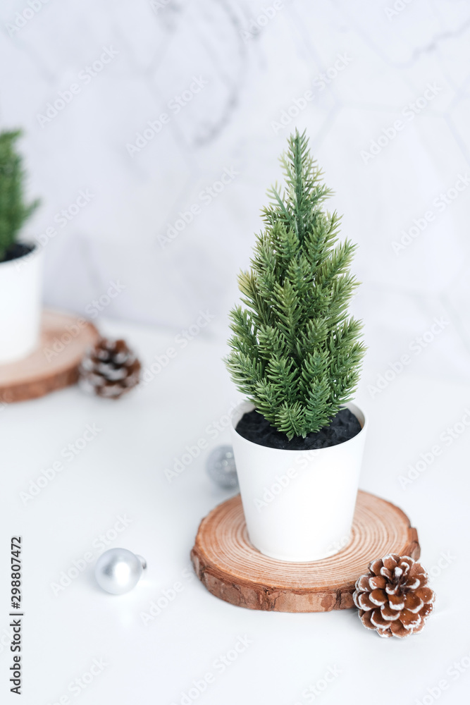 Aufkleber christmas tree with pine cone,decor xmas ball on wood log at white table and marble tile wall background.clean minimal simple style.holiday still life with space to adding text