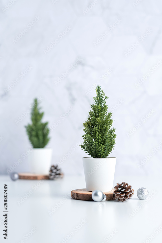 Poster christmas tree with pine cone,decor xmas ball on wood log at white table and marble tile wall background.clean minimal simple style.holiday still life with space to adding text
