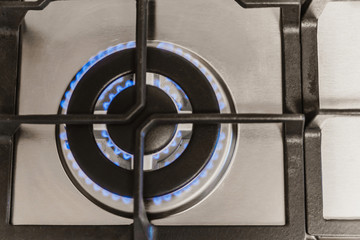 kitchen gas stove with burning propane gas fire. Close-up shot of blue fire from home kitchen stove. Gas stove with a burning flame of propane gas. Concept of industrial resources and economy.