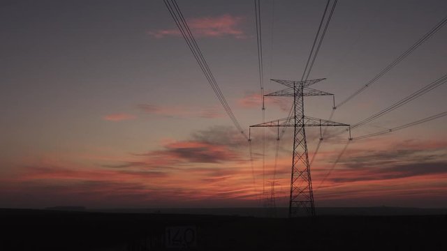 Time lapse at sunrise electricity pylon and high voltage power line at sunset. electricity pylon in a row on the background of beautiful cloudy sky.