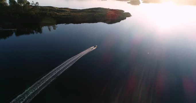 Aerial footage of speed booat crossing peaceful blue water near bautiful island. 
