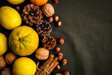 Pile of fresh fruits, cones and nuts on the dark green fabric. Thanksgiving and halloween backgrounds with copyspace concept. Autumn flatlay. 