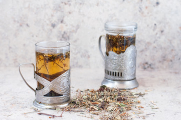 Two glasses of tea in old cupholders on a gray background.