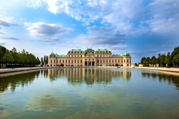Obraz premium Panoramic views of the Belvedere Palace in Vienna, Austria. In front is a large lake and above is a blue sky with clouds.