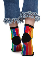 Close-up back shot of female shins in striped rainbow-coloured socks with black heels, toes and rims. The girl in blue jeans with fringe is standing on tiptoe on the white background.