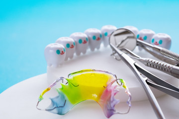 Dental retainer orthodontic appliance and dental tools on the blue background. - obrazy, fototapety, plakaty