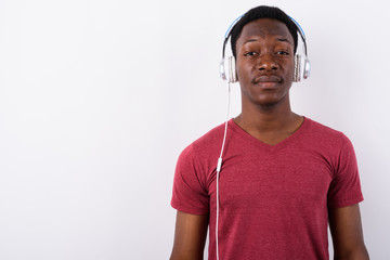 Young handsome African man listening to music against white back